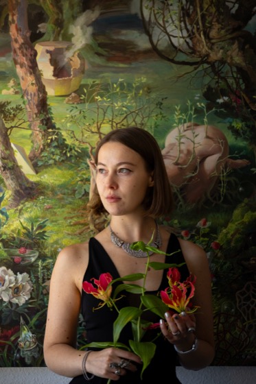 Gast mit Blumen vor einem farbenfrohen Gemälde an der Vernissage