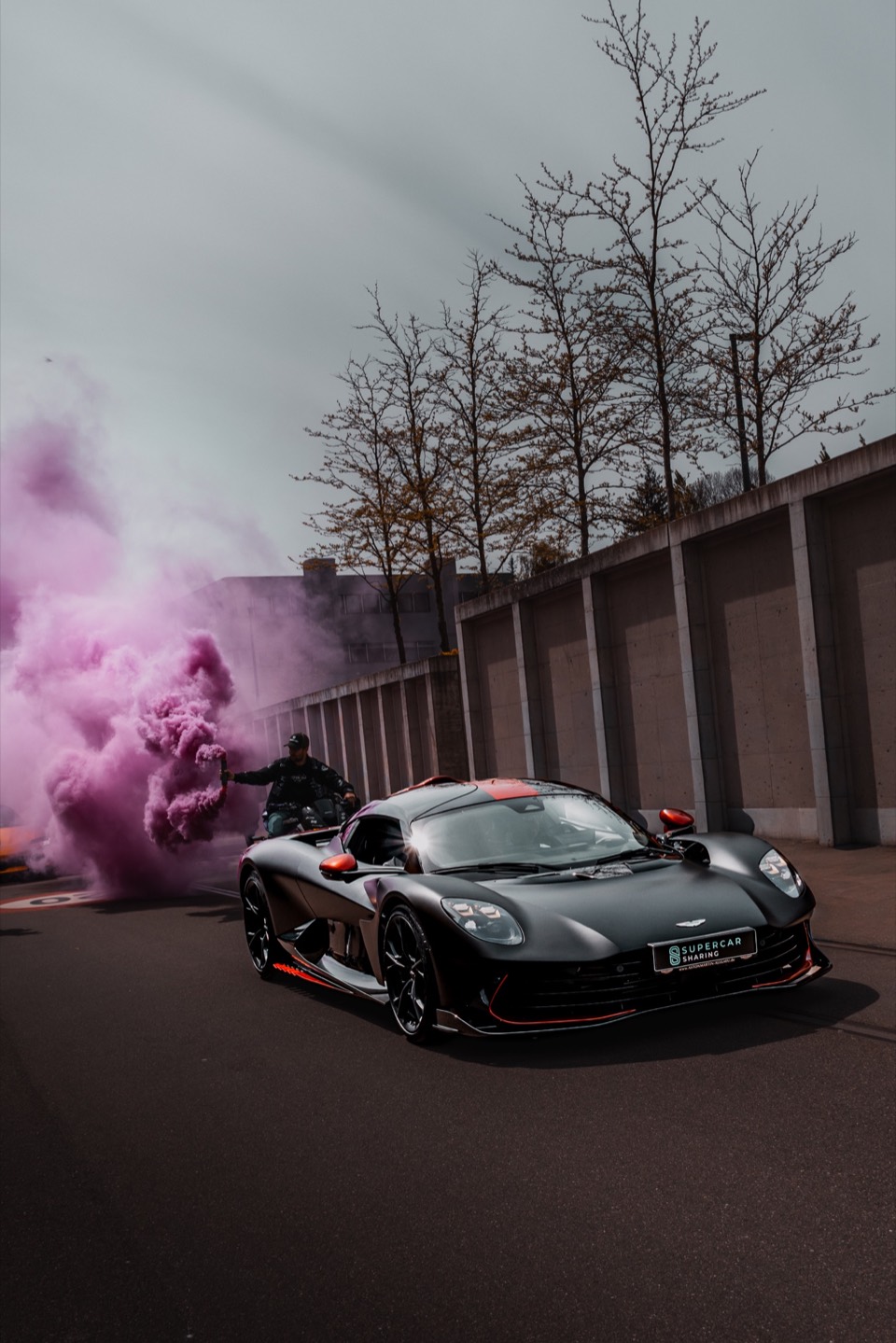 Schwarzer Sportwagen vor einer pinken Rauchkulisse
