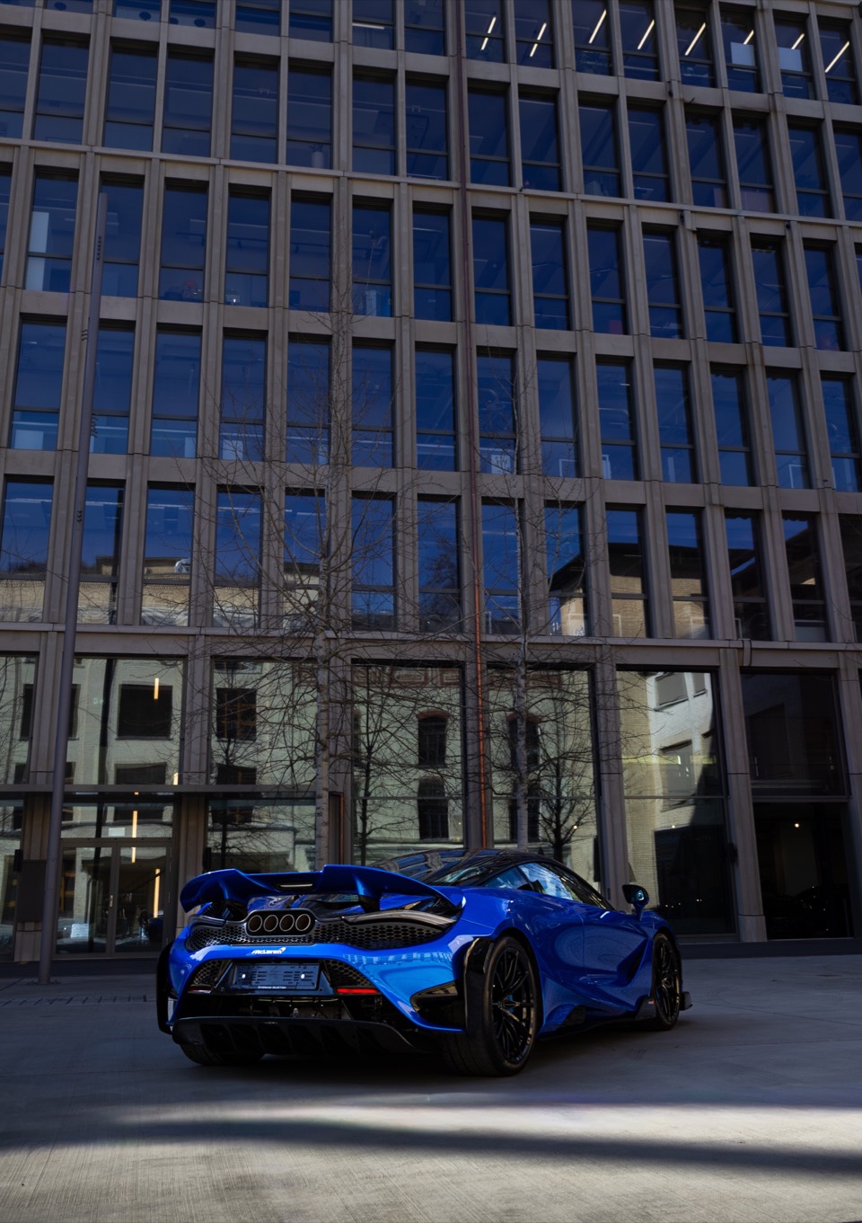 Blauer McLaren vor einer modernen Fassade