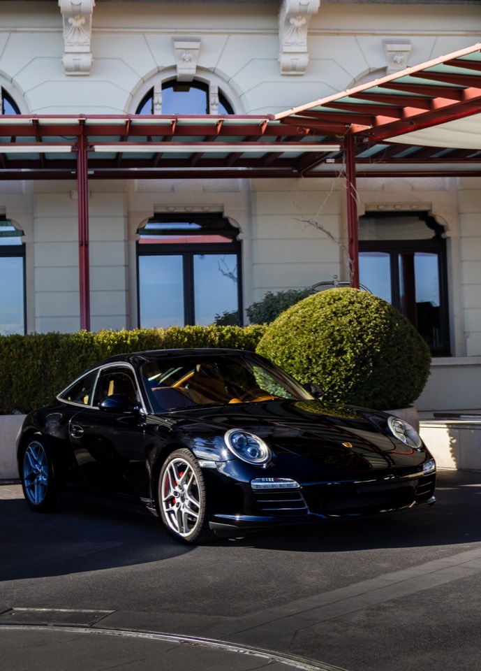 Schwarzer Porsche vor einer eleganten Hotelfassade